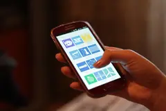 Смартфон в ръка, на екрана се виждат иконите на приложения