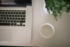 Лаптоп, чаша и растение на бяло бюро